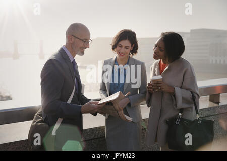 Business people reading newspaper on sunny urban bridge Stock Photo