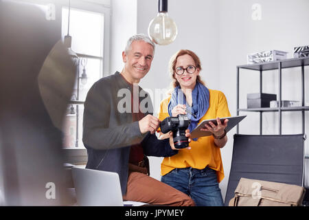 Portrait smiling, confident photographers with digital camera and digital tablet in office Stock Photo