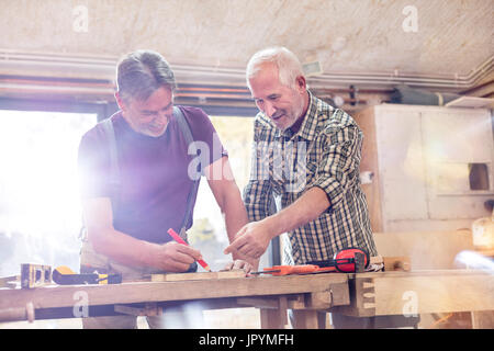 Male carpenters marking and measuring wood in workshop Stock Photo