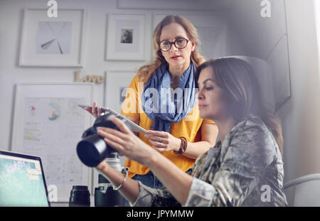Female photographers with digital camera and digital tablet in office Stock Photo