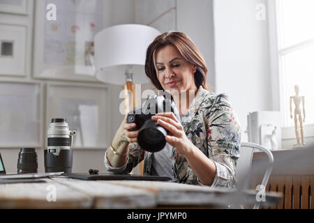 Female photographer using digital camera in office Stock Photo