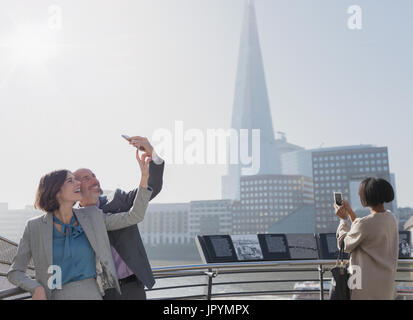 Business couple taking selfie with camera phone, London, UK Stock Photo