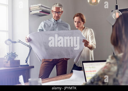Architects reviewing blueprints in office Stock Photo