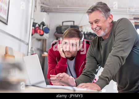 Male carpenters working at laptop in workshop Stock Photo