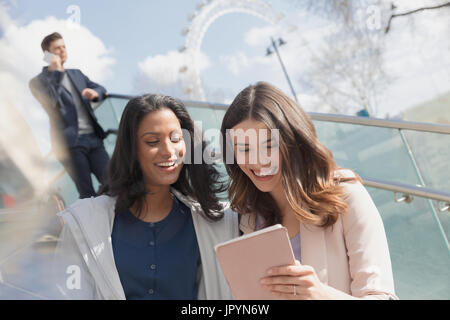 Smiling businesswomen using digital tablet outdoors Stock Photo