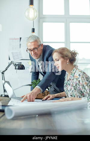 Architects discussing, reviewing blueprints in office Stock Photo