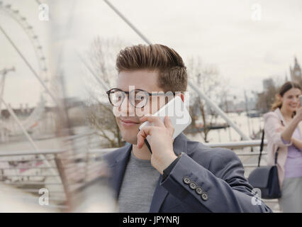 Man talking on cell phone on urban bridge near Millennium Wheel, London, UK Stock Photo