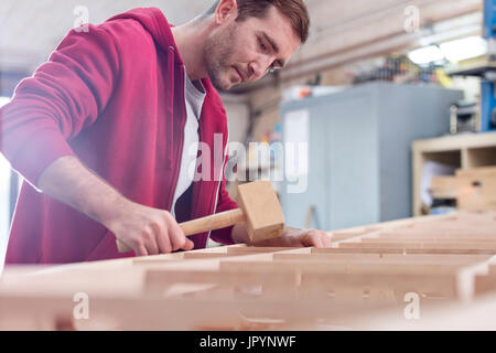 Male carpenter using wood mallet on boat in workshop Stock Photo