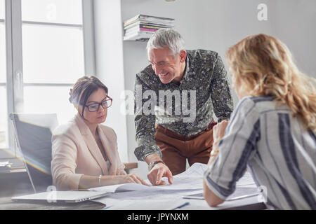 Architects discussing and reviewing blueprints in conference room meeting Stock Photo