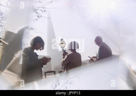 Business people using cell phones in sunny city, London, UK Stock Photo
