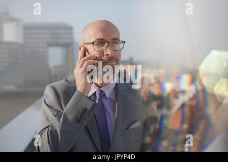 Businessman talking on cell phone on busy, urban pedestrian bridge Stock Photo