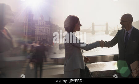 Silhouette business people handshaking on sunny bridge over River Thames, London, UK Stock Photo