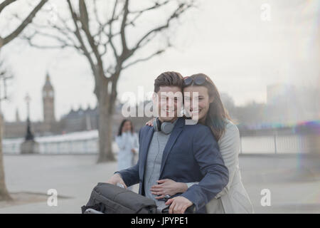 Portrait smiling, hugging couple tourists with bicycle in urban park, London, UK Stock Photo