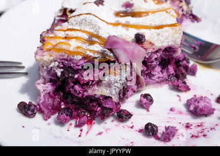Blueberry pie strudel Close up shot on white plate, pie partially eaten with two forks partially in background on each side Stock Photo