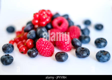 pile of mixed berries,  berry fruits on white background - rasberries, blueberries and currant Stock Photo