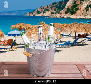 Three unopened bottles of beer inside ice bucket on beach background Stock Photo