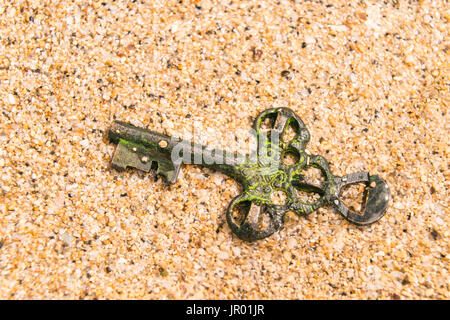 Treasure key lost in sand. Opportunity or Mystery concept. Stock Photo