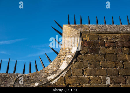 Detail close-up of Tudor era brick wall with a row of sharp black spikes on top edge Stock Photo