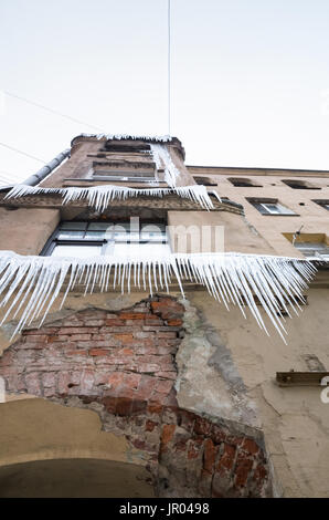 Large icicles hang on the facade of old living house. Winter in Saint-Petersburg, Russia Stock Photo