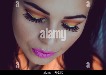 Detail of the face of a young dark-haired woman with extravagant make up, pink lips Stock Photo