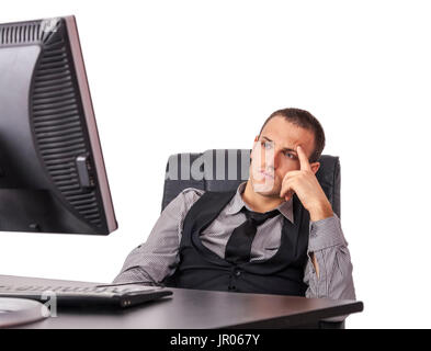 Tired young businessman sitting in front of his computer with a thinking attitude, isolated against a white background. Stock Photo