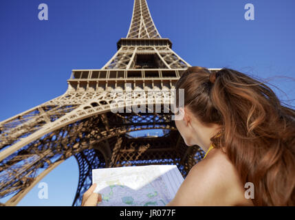 Touristy, without doubt, but yet so fun. Seen from behind young woman with map against Eiffel tower in Paris, France Stock Photo