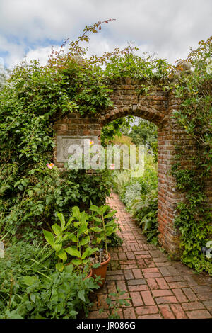 Inviting view through a red brick gate into Sissinghurst Castle Garden, Kent, England, United Kingdom. Stock Photo