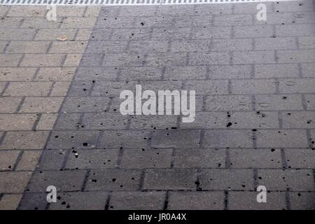 dirty sidewald of paving stones after heavy rainfall, rainwater and flood on a road Stock Photo