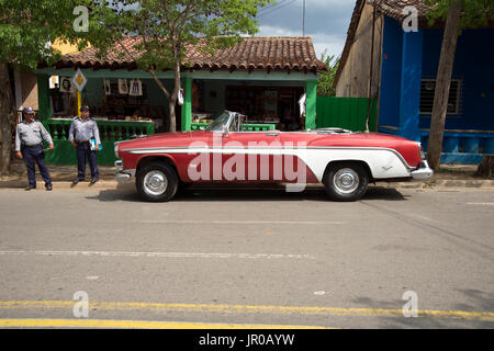 American cars in CubaTwo Cuban traffic policemen stand beside a 1950's classic American car parked in Vinales Cuba Stock Photo