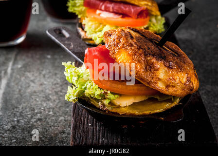 Mexican Tortilla de patatas rellena de jamón serrano - casserole with potato, eggs, sandwich with meat, lettuce, cheese, tomatoes. In portioned frying Stock Photo