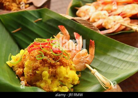 Ketan Serundeng Udang. Turmeric Sticky Rice with Roasted Coconut and Shrimp Satay Stock Photo