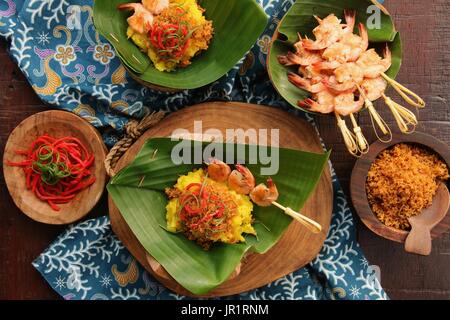 Ketan Serundeng Udang. Turmeric Sticky Rice with Roasted Coconut and Shrimp Satay Stock Photo