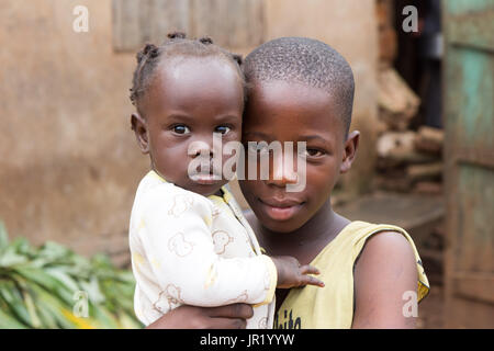 Lugazi, Uganda. June 09 2017. A young African girl holding her baby sister in her arms Stock Photo
