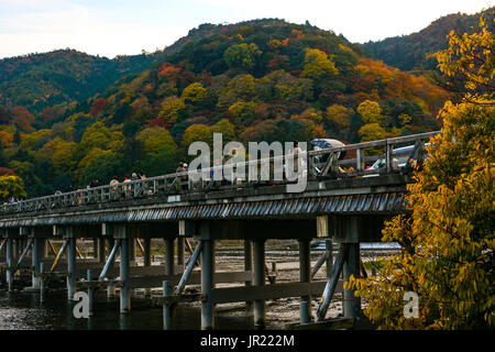 KYOTO, JAPAN - NOVEMBER 18, 2016 - Tourists enjoying the colors of autumn along the Togetsu Bridge in Kyoto's Arashiyama area during the fall season Stock Photo