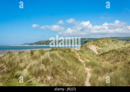 stunning landscape image of the sea and beach behind the sand dunes, with a beautiful bright blue sky and white fluffy clouds. Stock Photo