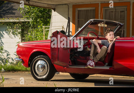 A Caucasian Teenage Boy With Brown Wavy Hair Sits With His Arm Over The Seat Of A 1960 Plymouth Valiant Convertible Stock Photo
