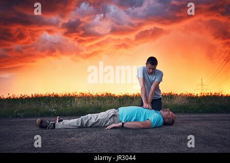 Dramatic resuscitation on the road during storm at the spectacular colorful sunset. Themes rescue, help and hope. Stock Photo