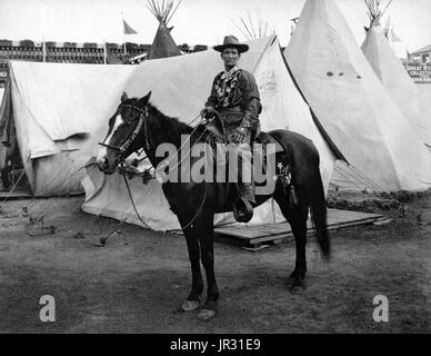 Calamity Jane, on horseback, wearing an elaborate Western costume, in front of tipis and tents at the Pan-American Exposition in Buffalo, New York, 1901. Martha Jane Canary (May 1, 1852 - August 1, 1903), better known as Calamity Jane, was an American frontierswoman and professional scout. She received little to no formal education and was illiterate. She worked as a dishwasher, a cook, a waitress, a dance-hall girl, a nurse, and an ox team driver. In 1874, she found work as a scout at Fort Russell. In 1876, she settled in the area of Deadwood and became friendly with Wild Bill Hickok and Char Stock Photo