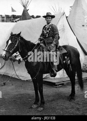 Calamity Jane, on horseback, wearing an elaborate Western costume, in front of tipis and tents at the Pan-American Exposition in Buffalo, New York, 1901. Martha Jane Canary (May 1, 1852 - August 1, 1903), better known as Calamity Jane, was an American frontierswoman and professional scout. She received little to no formal education and was illiterate. She worked as a dishwasher, a cook, a waitress, a dance-hall girl, a nurse, and an ox team driver. In 1874, she found work as a scout at Fort Russell. In 1876, she settled in the area of Deadwood and became friendly with Wild Bill Hickok and Char Stock Photo