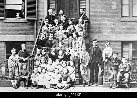 Bell, on top step with Dexter King, founder of the school, and Ira Allen, chairman of school committee, three steps down are teachers Annie Bond, Sarah Fuller, Ellen Barton, and Mary True, students are seated on the steps and standing on the sidewalk at entrance to the Pemberton Square School (Boston School for the Deaf). Alexander Graham Bell (March 3, 1847 - August 2, 1922) was a Scottish-American speech therapist and inventor of the telephone. Bell followed his father and grandfather into the speech therapy profession, but also studied sound waves and the mechanics of speech. By 1871, he ha Stock Photo