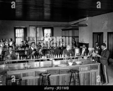 Chemistry laboratory/classroom with students at the Tuskegee Institute, Tuskegee, Alabama. George Washington Carver stands second from right, facing front (framed by doorway). George Washington Carver (1864 - January 5, 1943) was an African-American scientist, botanist, educator, and inventor born into slavery. In 1891 he attended and studied botany at Iowa State Agricultural College where he was the first black student, and later taught as the first black faculty member. His reputation is based on his research into and promotion of alternative crops to cotton, such as peanuts, soybeans and sw Stock Photo