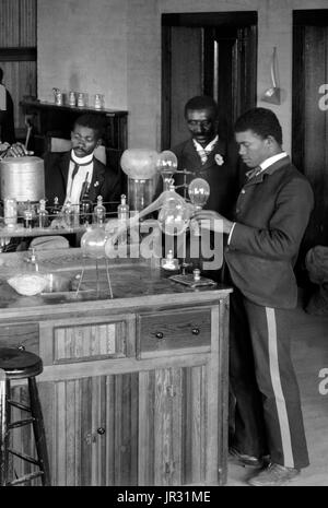 Chemistry laboratory/classroom with students at the Tuskegee Institute, Tuskegee, Alabama. George Washington Carver stands second from right, facing front (framed by doorway). George Washington Carver (1864 - January 5, 1943) was an African-American scientist, botanist, educator, and inventor born into slavery. In 1891 he attended and studied botany at Iowa State Agricultural College where he was the first black student, and later taught as the first black faculty member. His reputation is based on his research into and promotion of alternative crops to cotton, such as peanuts, soybeans and sw Stock Photo