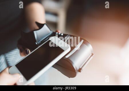Man using NFC technology on smart phone to pay bill Stock Photo