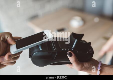 Man using NFC technology on smart phone to pay bill Stock Photo