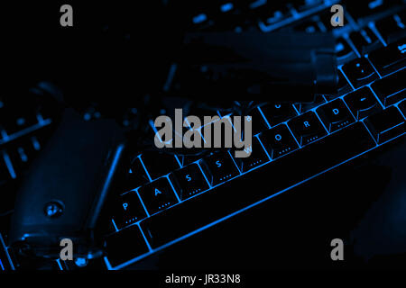 Password text and pistol on the illuminated buttons of the keyboard by night. Internet safety concept. Stock Photo
