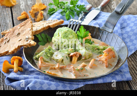 Fresh chanterelles with cream sauce and spinach bread dumplings in a frying pan Stock Photo