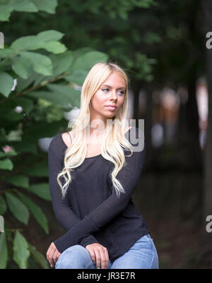 Pretty blond nineteen year old girl sitting in a garden Stock Photo