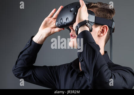 Man wearing virtual reality goggles. Studio shot, gray backgroun Stock Photo