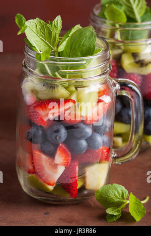 fruit salad in mason jar strawberry blueberry kiwi apple mint Stock Photo