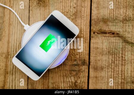 White smartphone charging on a charging pad. Wireless charging Stock Photo